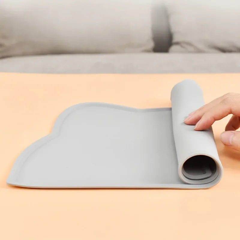 Gray silicone pet feeding mat being rolled up, non-slip surface for dog or cat meals