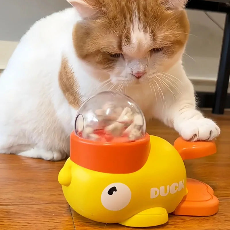 Orange and white cat playing with yellow duck-shaped interactive treat dispenser toy