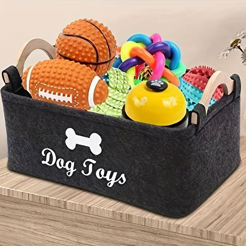 Black felt dog toy basket with bone design, filled with colorful chew toys, balls, and rope toys for pets